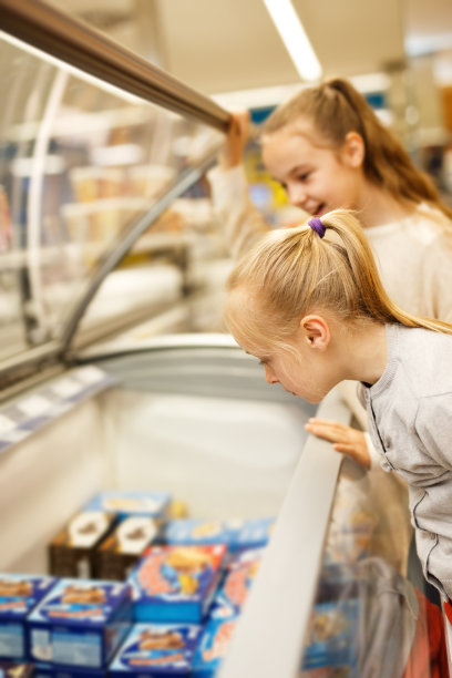 两个小妹妹站在冰箱旁边挑选冷冻食品图片下载