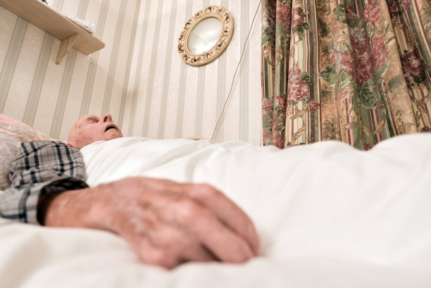 一位年老体弱的男子出院后躺在床上睡着了。图片下载