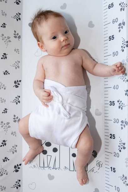 快乐的小女孩躺在换尿布垫上，穿着尿布。图片下载