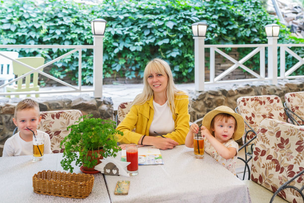 带着两个孩子的年轻母亲坐在咖啡馆享受美食图片下载