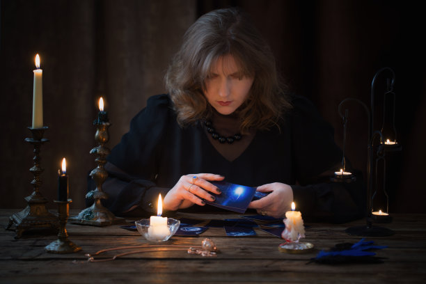 成熟的女人在黑暗的背景下用纸牌猜测图片下载