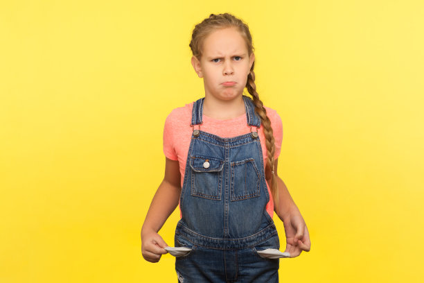 一幅沮丧的小女孩的画像穿着牛仔工装裤，带着辫子，口袋空空，身无分文图片下载