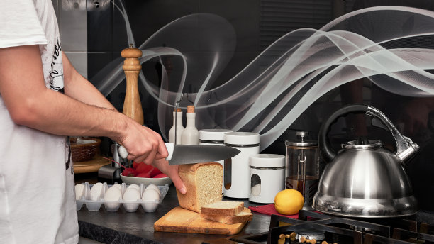 一个年轻人切面包给自己做早餐图片下载