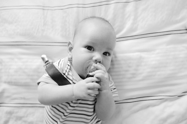 一个新生儿躺在床上，抱着他的假人。图片下载