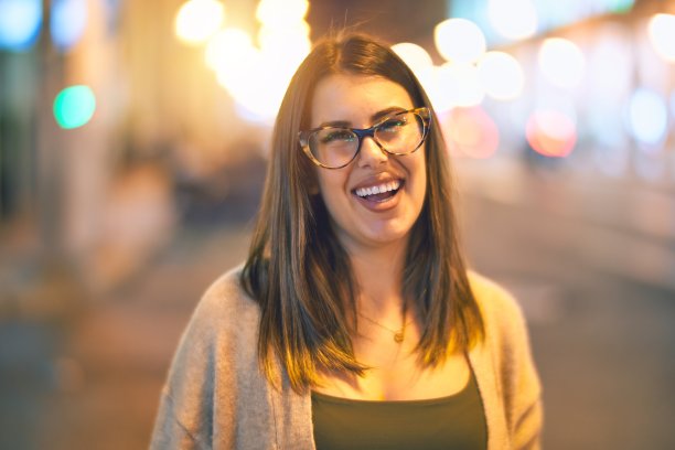 年轻漂亮的女人微笑着，快乐而自信。微笑着站在小镇的街道上图片下载