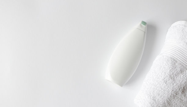 沐浴露或洗发水塑料容器模型和毛巾在白色背景与复制空间，俯视图。浴室平。概念卫生横旗格式素材图片