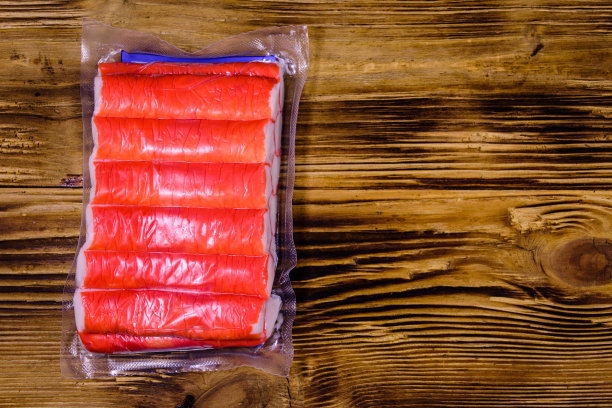 真空包装的蟹棒放在一张木桌上。俯视图图片下载