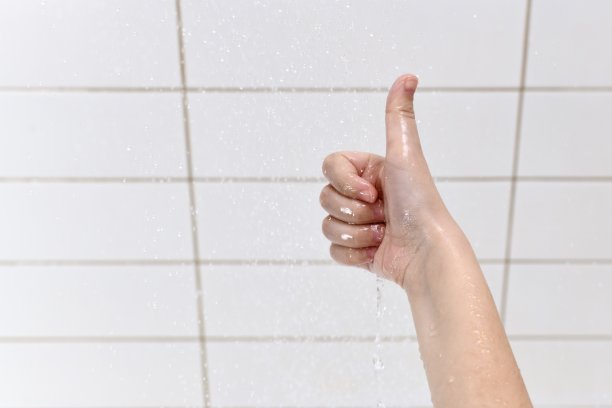 孩子的手掌向前伸展，做一个拳头的手势，拇指伸到水滴下。图片下载