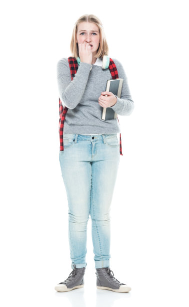 年轻的初中生穿着毛衣，拿着书，戴着耳机站在白色背景前图片下载