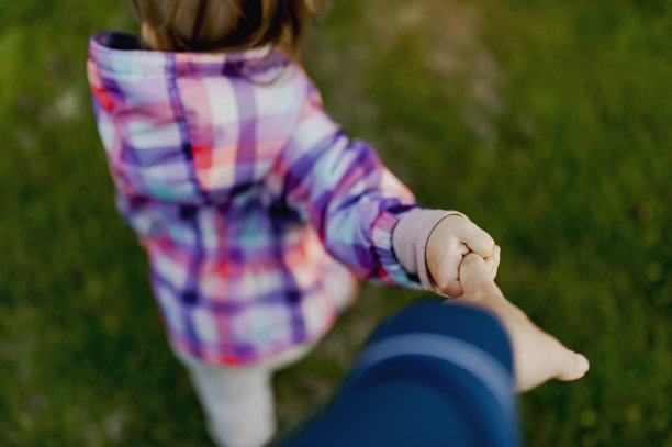父母对蹒跚学步的孩子牵着他们的手穿过院子的看法图片下载