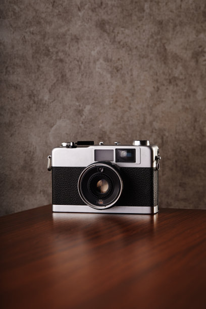 老式的模拟测距电影相机放在木桌前的混凝土纹理墙作为背景图片下载