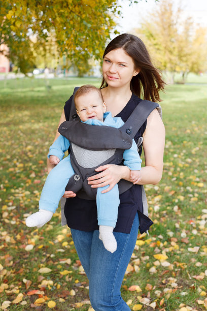 蹒跚学步的婴儿坐在吊带妈妈，抱着孩子在一个直立的位置，没有负荷图片下载