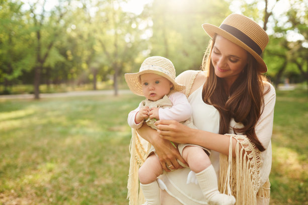 日落时分，时髦的妈妈和她的宝宝在夏日公园里玩耍。母亲节概念。图片下载