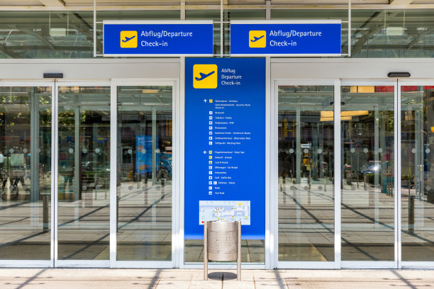 机场候机楼大门入口和带有德语和英语信息的自动玻璃门。现代机场玻璃墙通道窗户和门。航站楼入口，自动玻璃门。图片下载