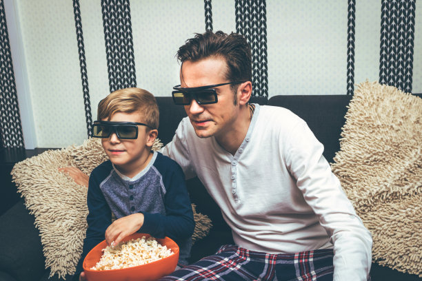 爸爸和儿子在家看电影，吃爆米花。图片下载