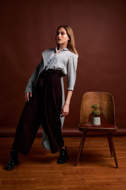 漂亮的年轻女性，穿着经典的套装，黑色的鞋子和灰色的外套。古董椅子。女人的衣服。图片下载