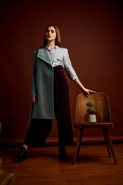 漂亮的年轻女性，穿着经典的套装，黑色的鞋子和灰色的外套。古董椅子。女人的衣服。图片下载