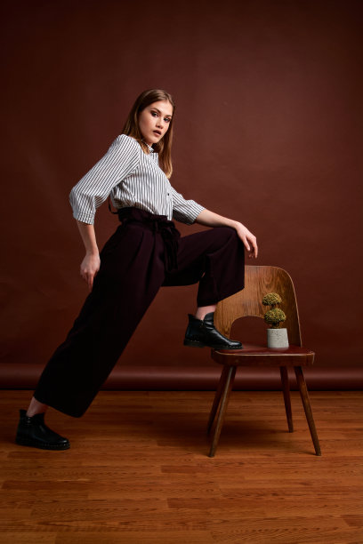 漂亮的年轻女性，穿着经典的套装，黑色的鞋子和灰色的外套。古董椅子。女人的衣服。图片下载