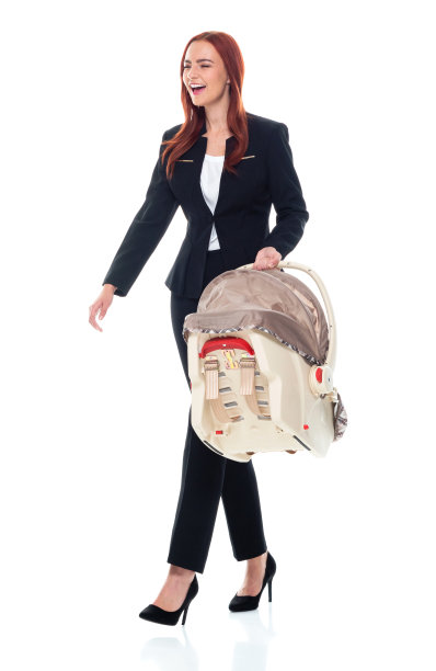 白人婴儿和人类年龄的女商人走在白色的背景，穿着商务服装，抱着汽车安全座椅图片下载