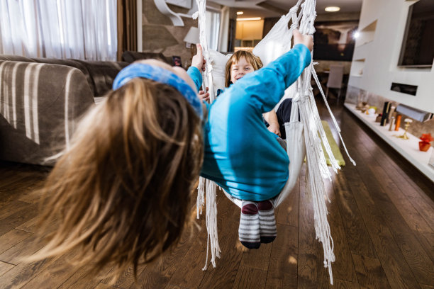 顽皮的男孩在家里荡秋千时玩得很开心。图片下载