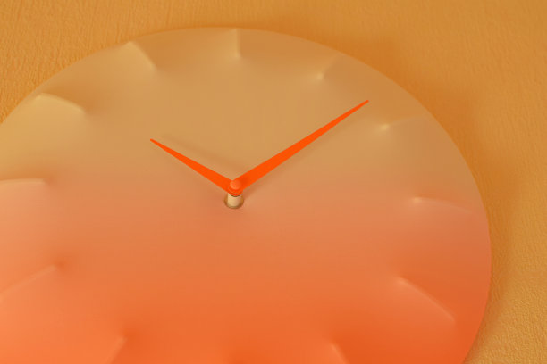 橙色的圆钟挂在亮黄色的墙上。图片下载