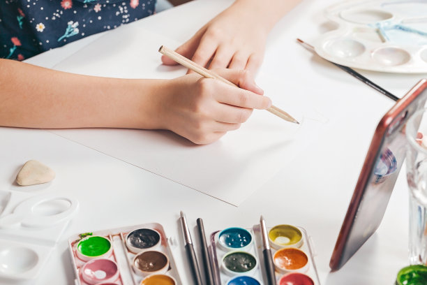 女孩用铅笔在白纸上画素描。用智能手机在线学习。的爱好。绘画。特写镜头图片下载