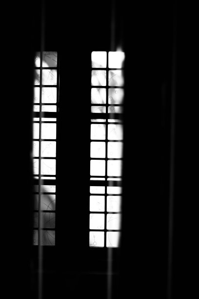 透过一扇关闭的窗户的黑色剪影看着橙色的天空，前景模糊了。图片下载