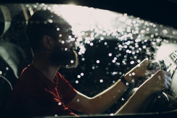 司机晚上坐在汽车的方向盘旁图片下载