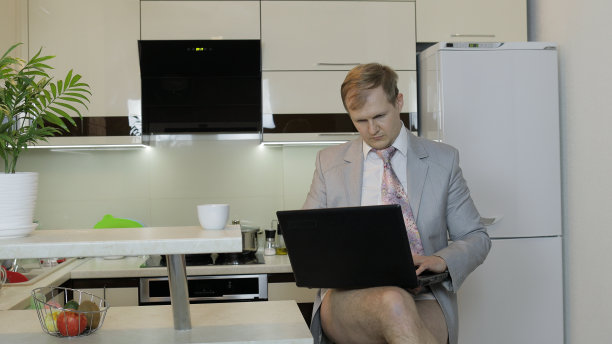 西装革履的商人在家里用笔记本电脑工作。远程工作图片下载