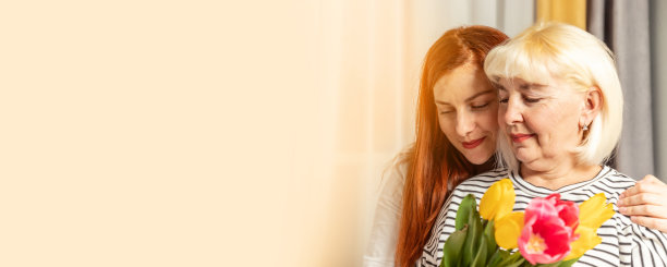 3月8日国际妇女节。一名成年金发女子在家里捧着一束郁金香和她的女儿拥抱图片下载