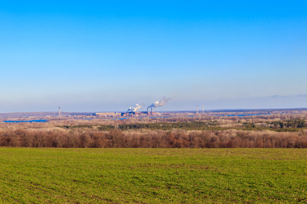 春天，绿油油的麦田和工厂的烟囱图片下载