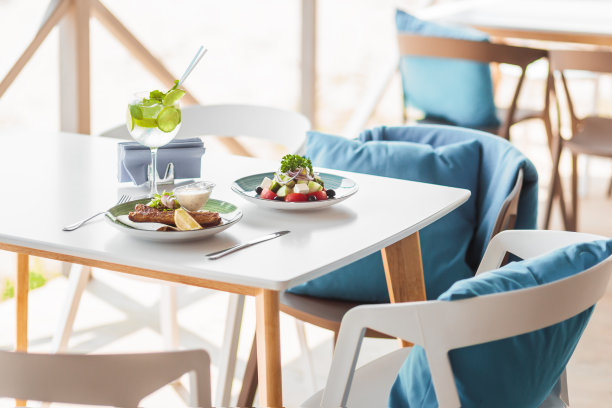 夏天作文在夏天操场上的桌椅上。美味的肉和生菜在桌子上。夏天冷却鸡尾酒。蓝色的枕头素材图片