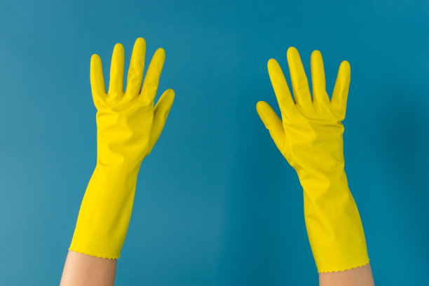 近手的未知白人妇女女女孩举起的手与保护性的黄色橡胶手套用于清洁或消毒对蓝色的墙壁背景在天图片下载