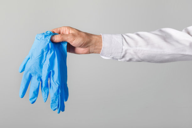 一名男子在冠状病毒大流行后将用过的手套和口罩扔进桶中。图片下载