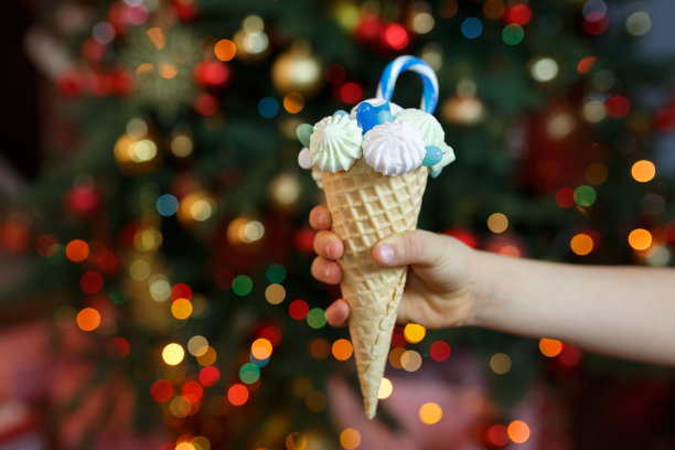 男孩手里拿着一个华夫蛋筒，里面装满了棉花糖和糖果图片下载