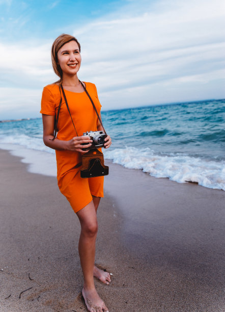 沙滩上拿着复古相机的女人图片下载
