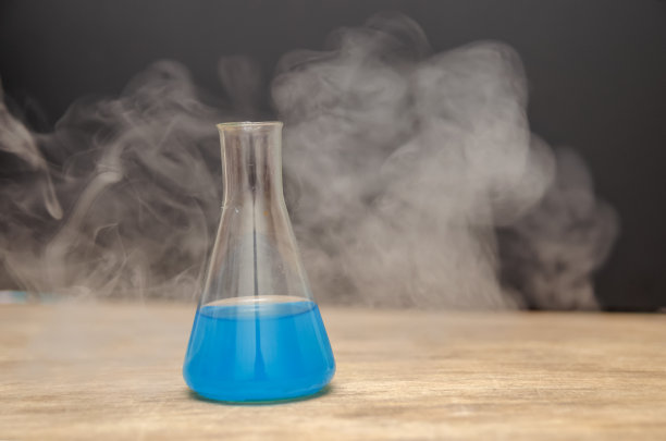 装有蓝色液体的烧瓶在黑色背景上冒烟。化学分析图片下载
