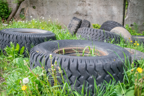 旧汽车轮胎躺在绿色的草地上。环境污染。图片下载