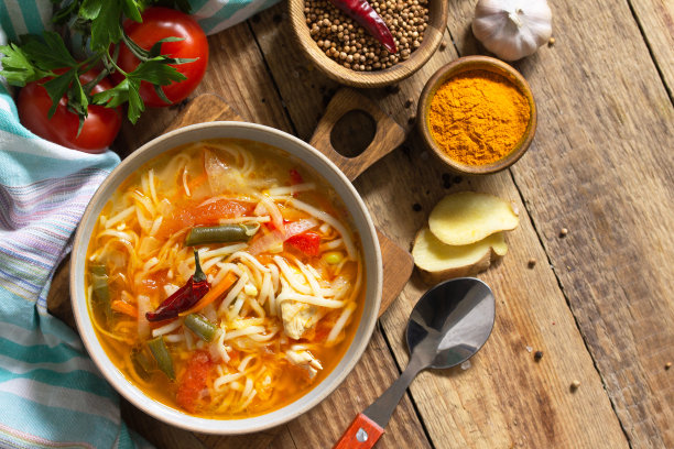 印度菜图克帕汤。热面条汤，鸡肉，生姜，香菜和香料放在一个特制的木桌上。俯视图平铺背景。副本的空间。图片下载