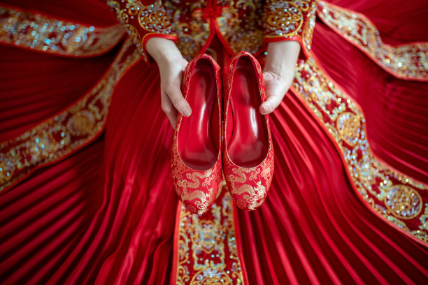 中国新娘穿着传统的婚纱，手拿红色的婚礼鞋图片下载
