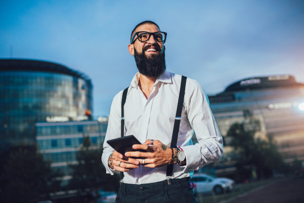 一个年轻的白人商人在户外拿着一个数码平板电脑。图片下载