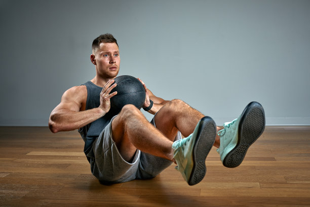 壮汉用健身球做运动。灰色背景上完美体格的男子照片。力量和动力图片下载