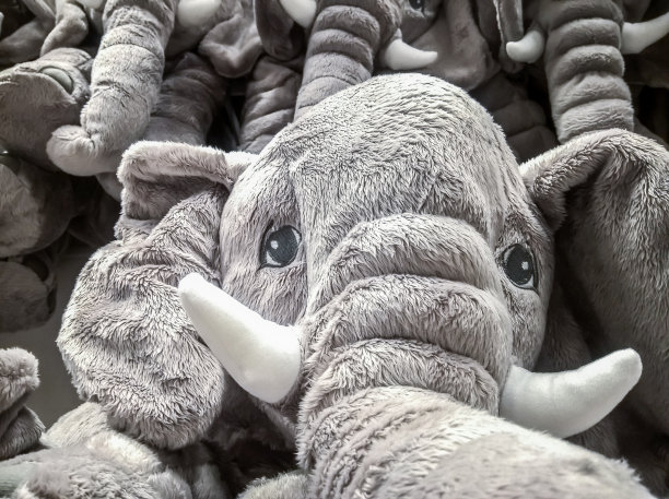 商店里有许多大象玩偶挂在墙上出售。图片下载