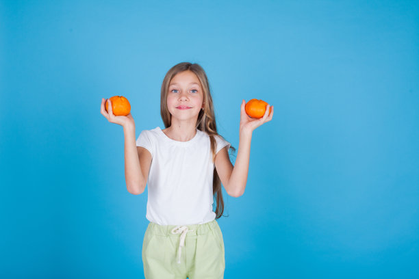 漂亮的小女孩拿着一个成熟的橘子图片下载