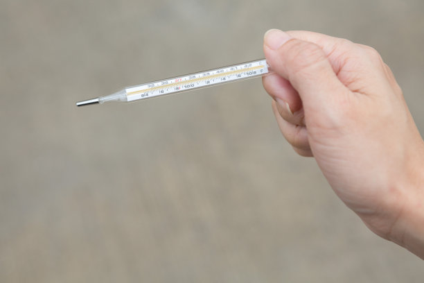 一只手拿着温度计，背景是棕色图片下载