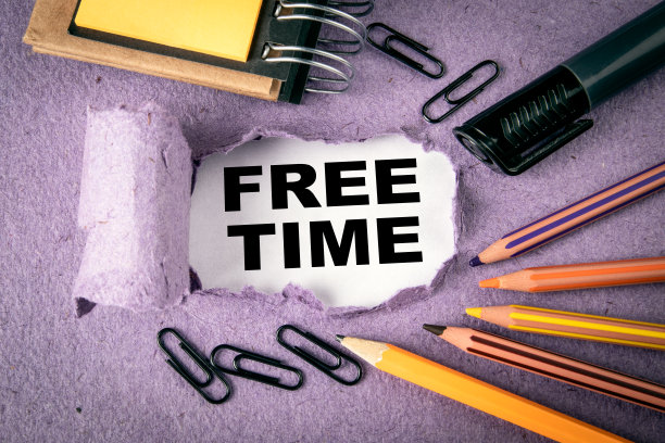 空闲时间的概念。文字在撕破的纸下。彩色铅笔和办公用品图片下载