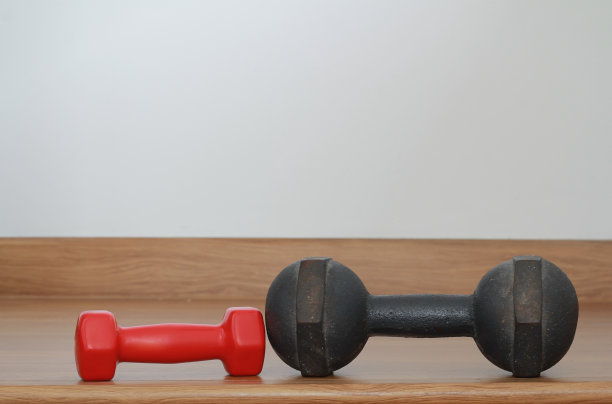 旧的铁哑铃和木制地板上的红色现代哑铃图片下载