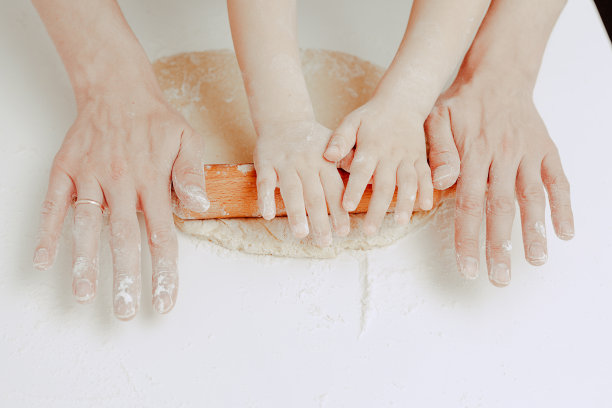 幸福的家庭在厨房。爸爸和儿子准备面团，烤饼干。休闲的生活方式，漂亮的孩子，节日概念，擀面杖，曲奇切割机和面团。图片下载