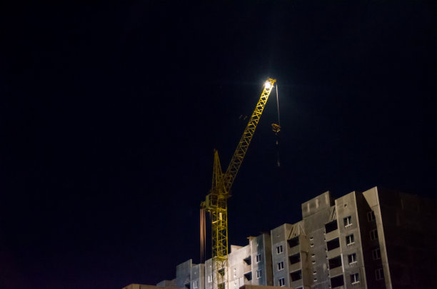 建筑工地。工业建筑起重机和夜空中建筑物的轮廓。美丽多彩的夜景。图片下载