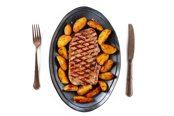 烤牛排和烤土豆角，从顶部拍摄在一个白色的背景图片下载